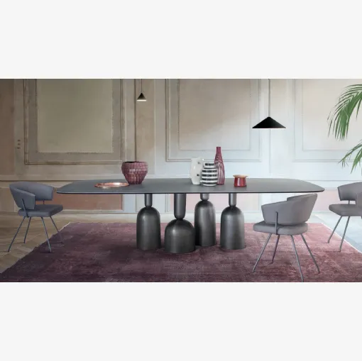 Tavolo Cop con piano in ceramica e base in metallo formata da elementi stilizzati ispirati a bottiglie, calici preziosi e coppe di champagne di Bonaldo
